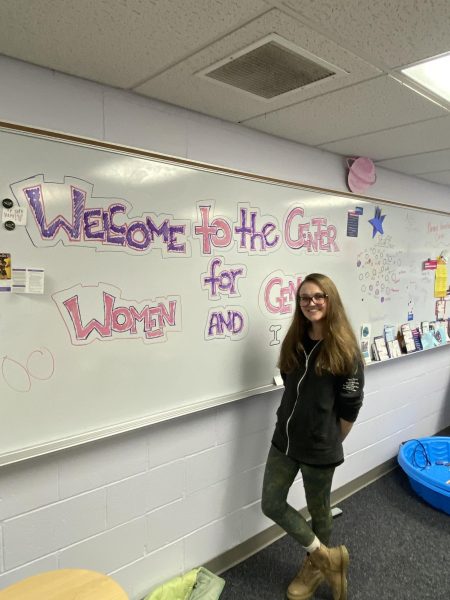 Lindsey Robison next to a whiteboard with the words "Welcome to the Center for Women and Gender"